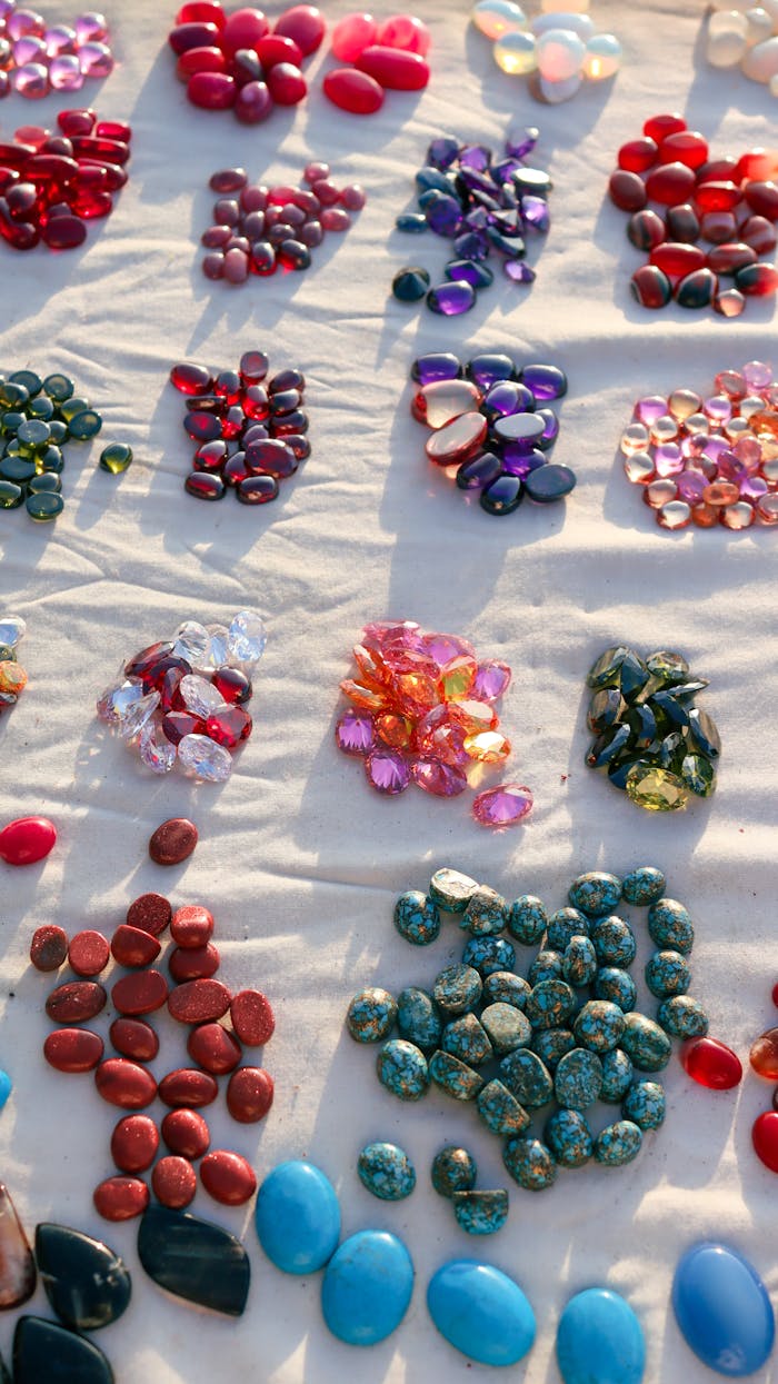 A vibrant collection of multicolored gemstones and pebbles displayed on a beige cloth under natural light.