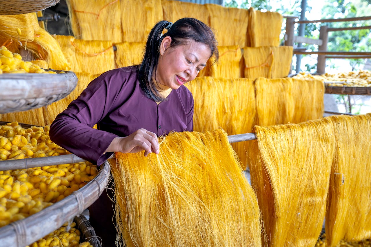 Woman working with silk threads in traditional Vietnamese silk village.