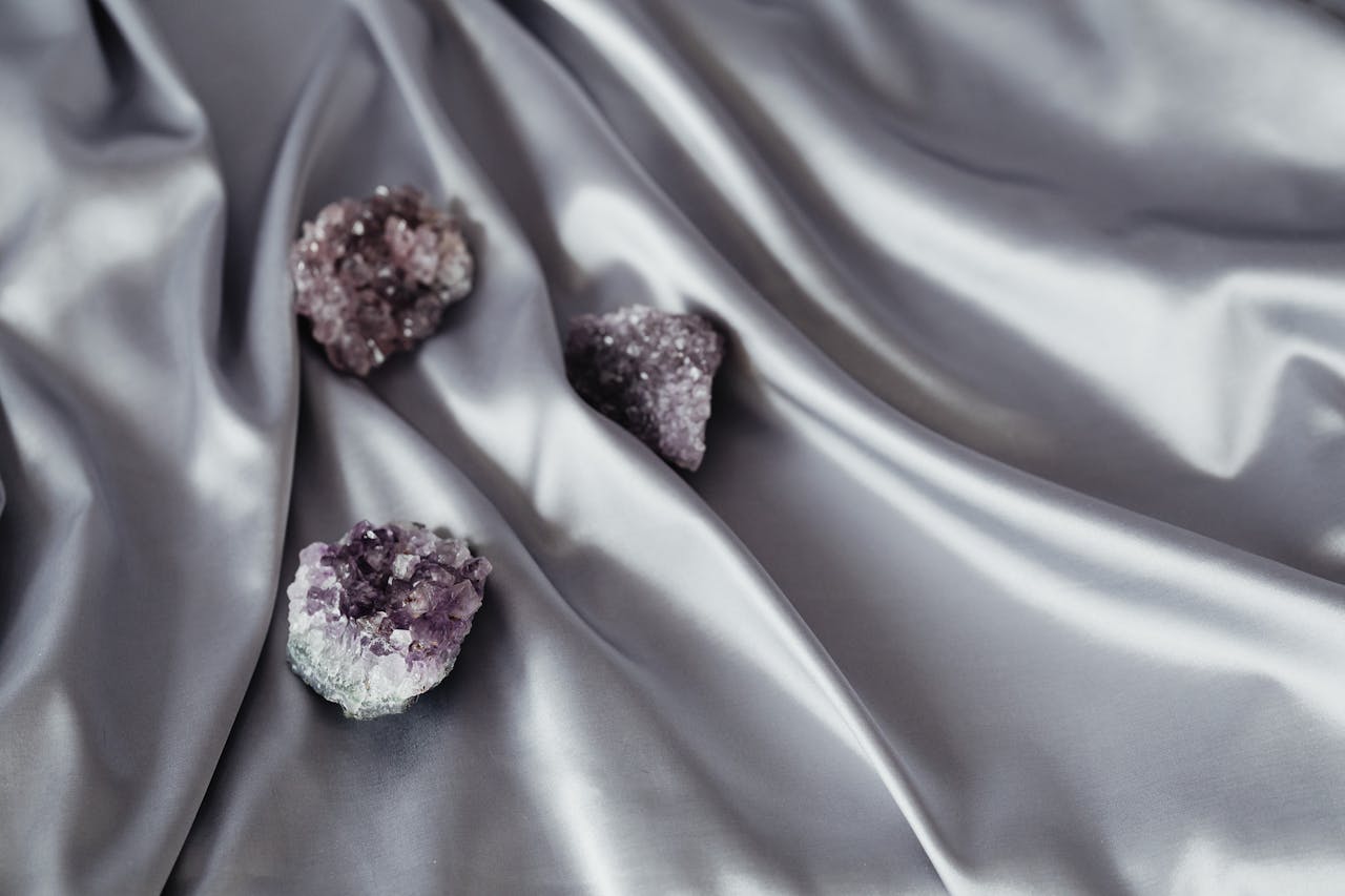 Chic amethyst quartz crystals elegantly placed on smooth gray silk fabric, highlighting texture and elegance.
